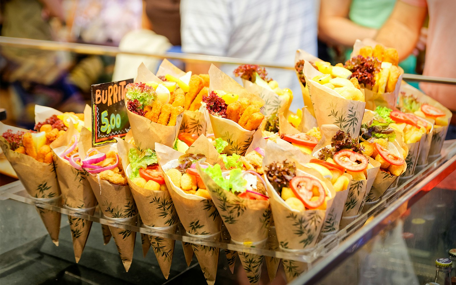 Street food cones with fries, vegetables, and chicken at a market stall.