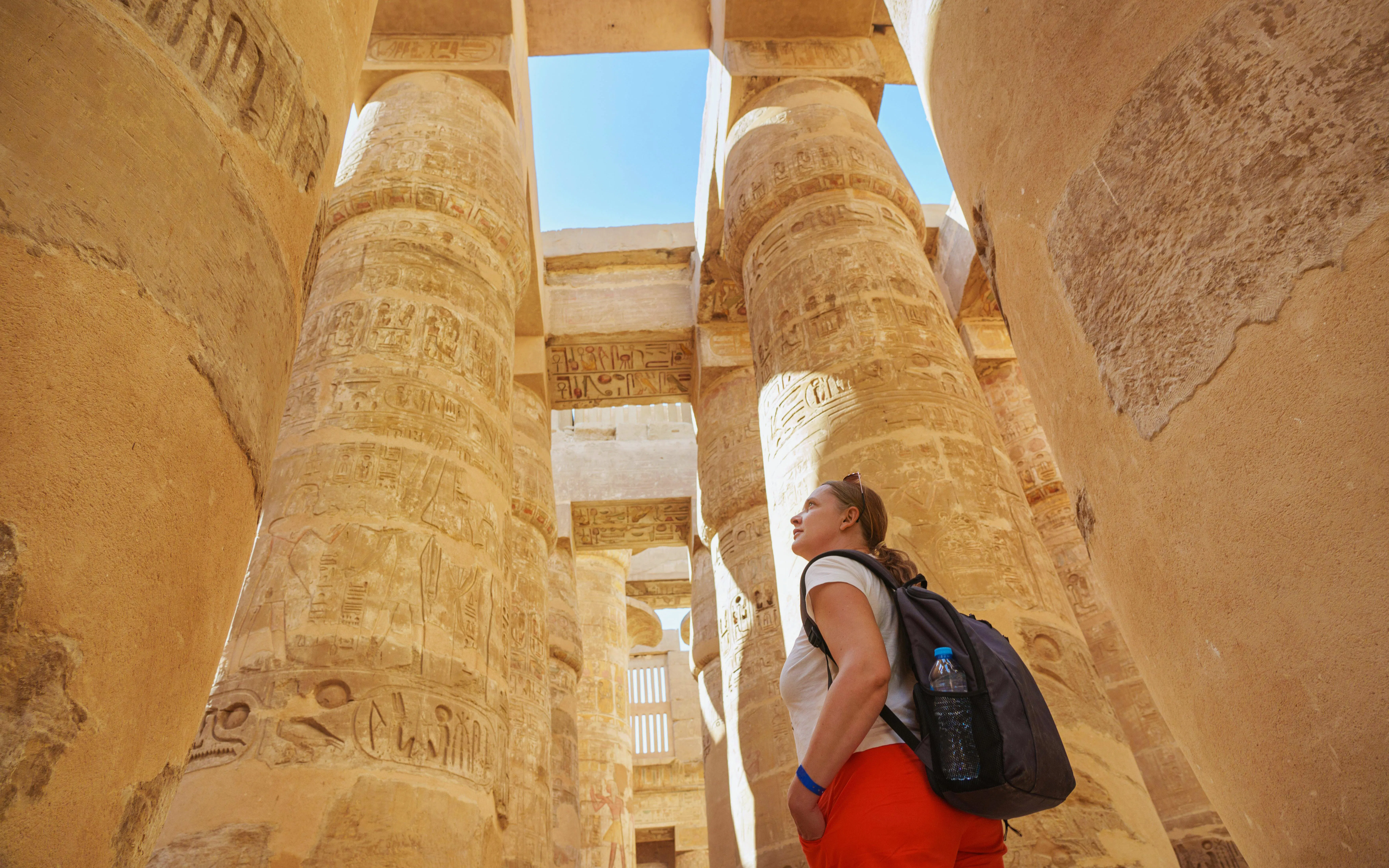 Tourist exploring Hypostyle Hall columns at Karnak Temple, Luxor.