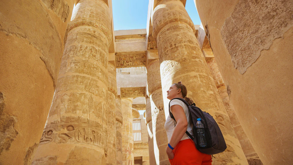 Tourist exploring Hypostyle Hall columns at Karnak Temple, Luxor.