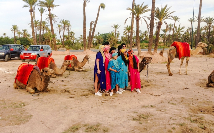 Group posing with camels in the Palmeraie during a sunset tour.