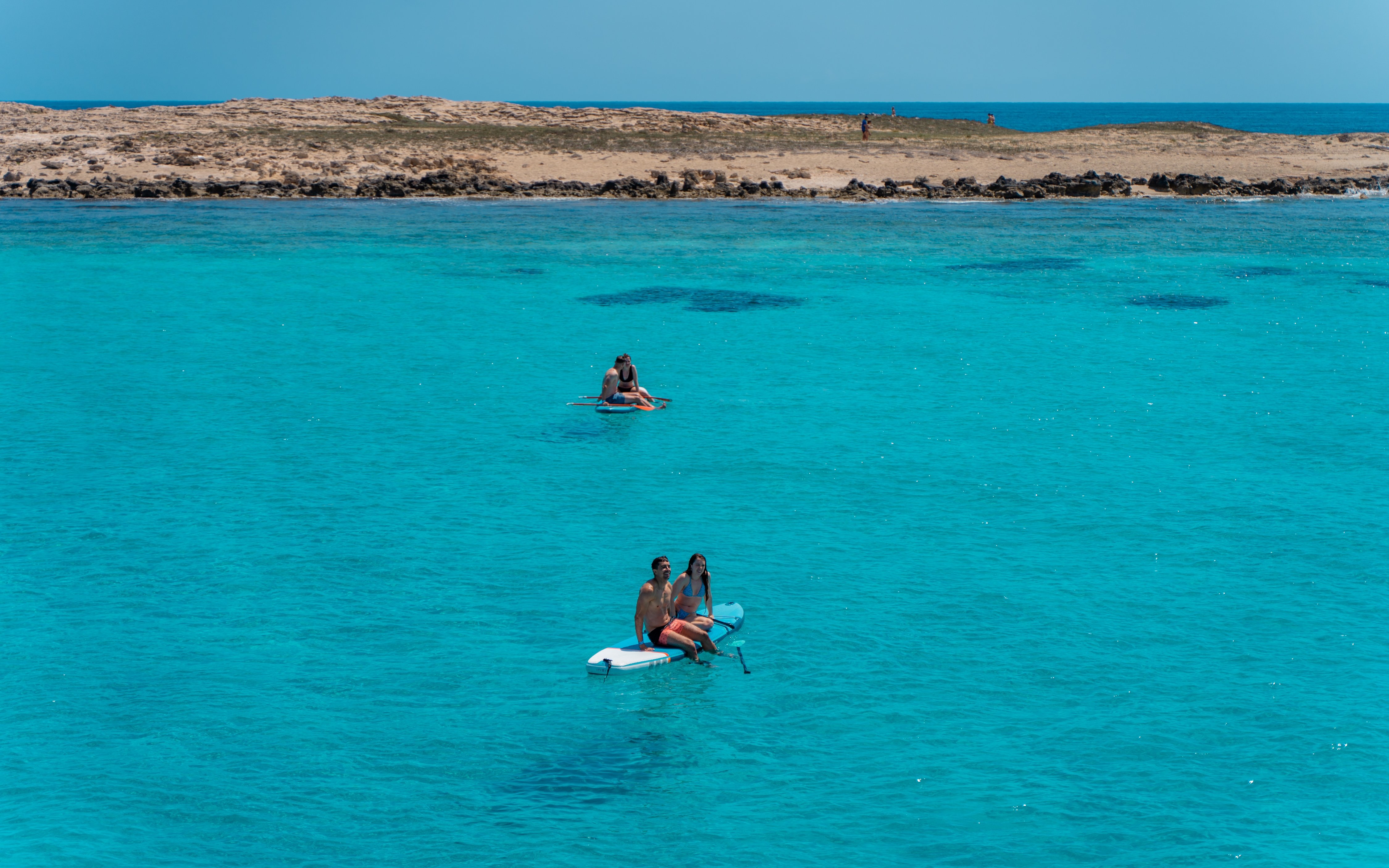 Friends paddleboarding on turquoise waters during Formentera Cruise Tour.