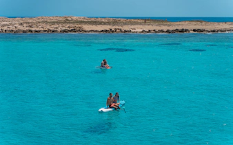 Friends paddleboarding on turquoise waters during Formentera Cruise Tour.