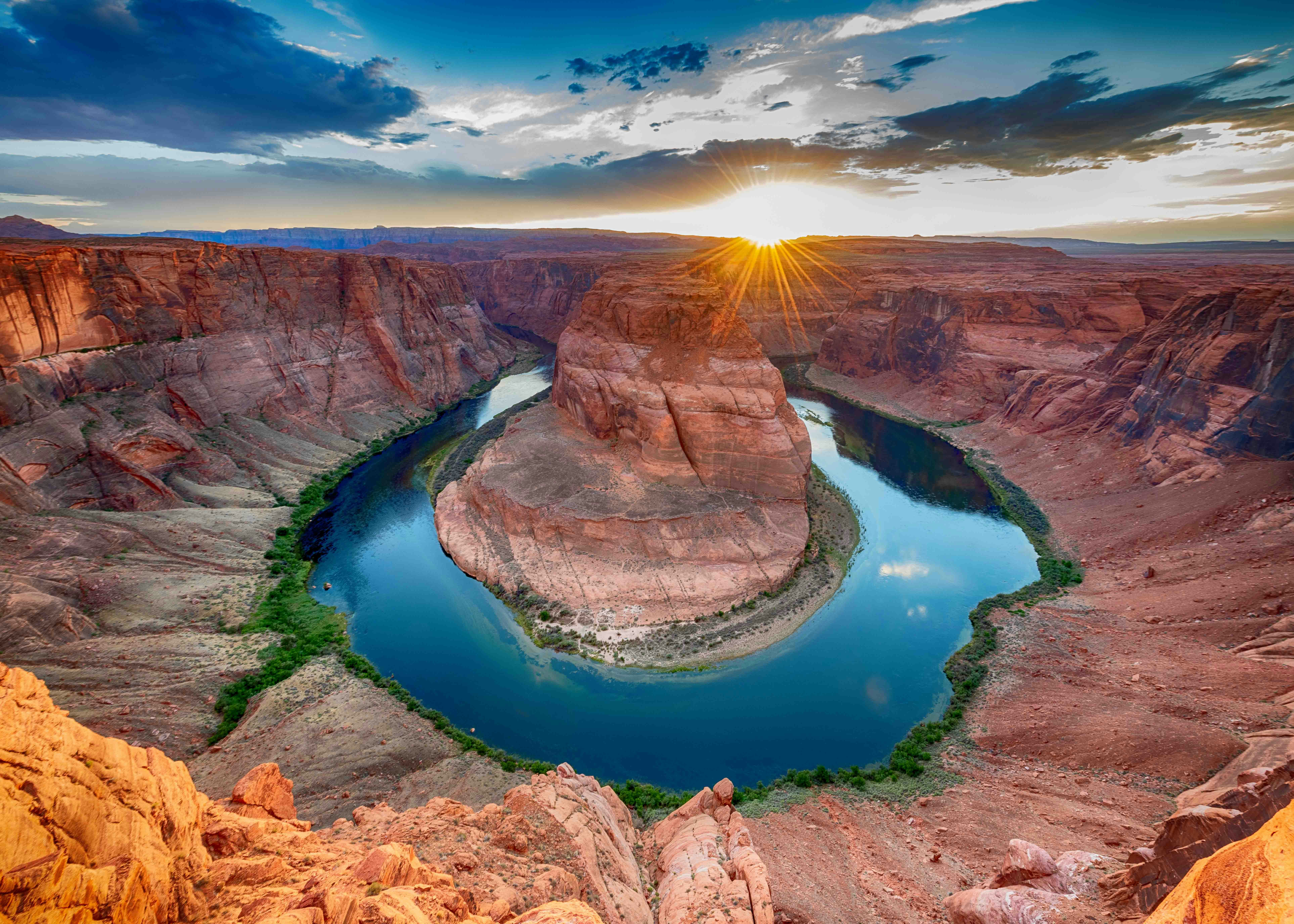 Horseshoe Bend at sunset with Colorado River curving around red rock formation.