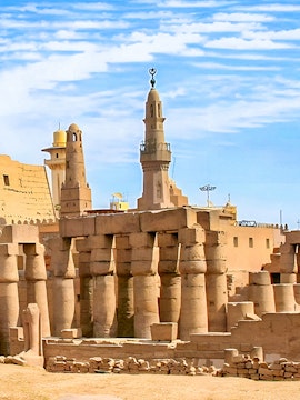Luxor Temple ancient columns and mosque minaret under a clear blue sky in Egypt.
