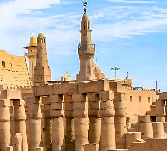 Luxor Temple ancient columns and mosque minaret under a clear blue sky in Egypt.