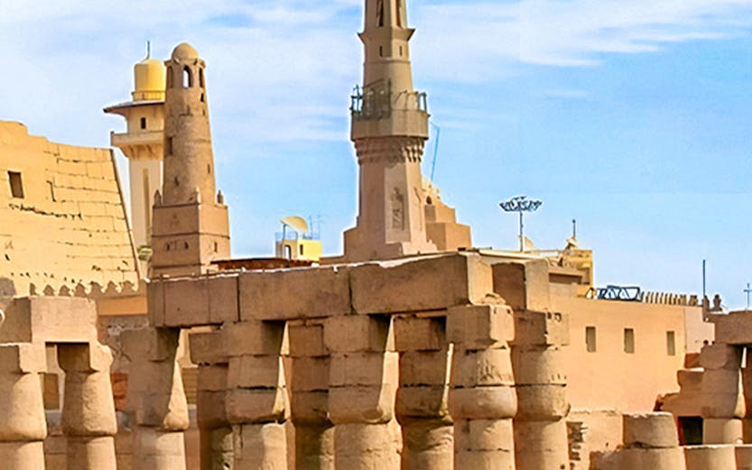 Luxor Temple ancient columns and mosque minaret under a clear blue sky in Egypt.