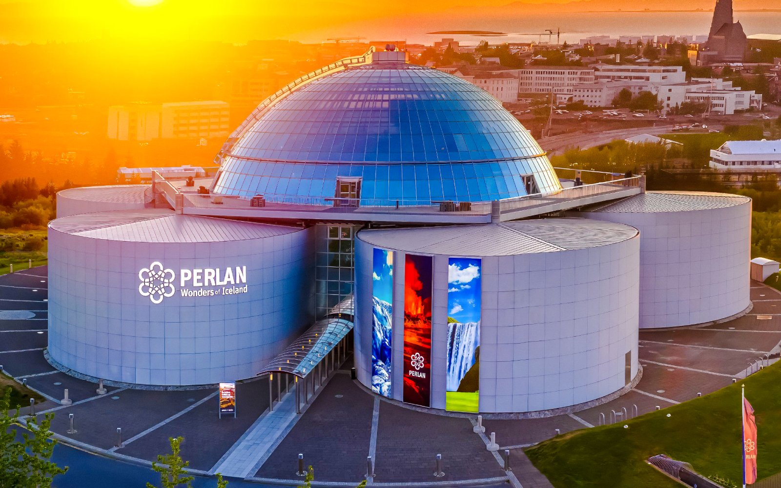 Aerial view of Perlan Museum's glass dome and exhibition halls in Reykjavik at sunset.