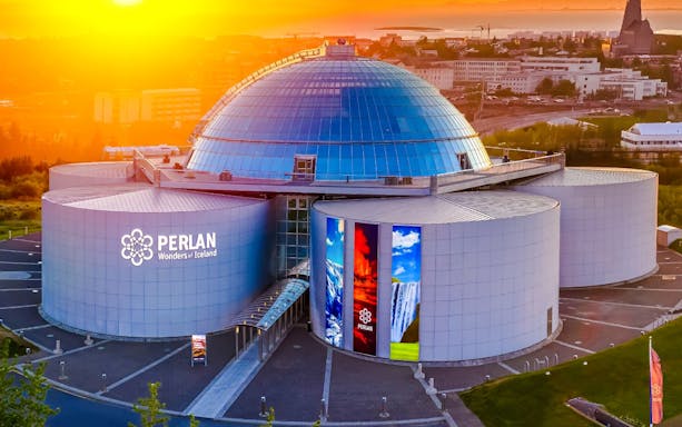 Aerial view of Perlan Museum's glass dome and exhibition halls in Reykjavik at sunset.