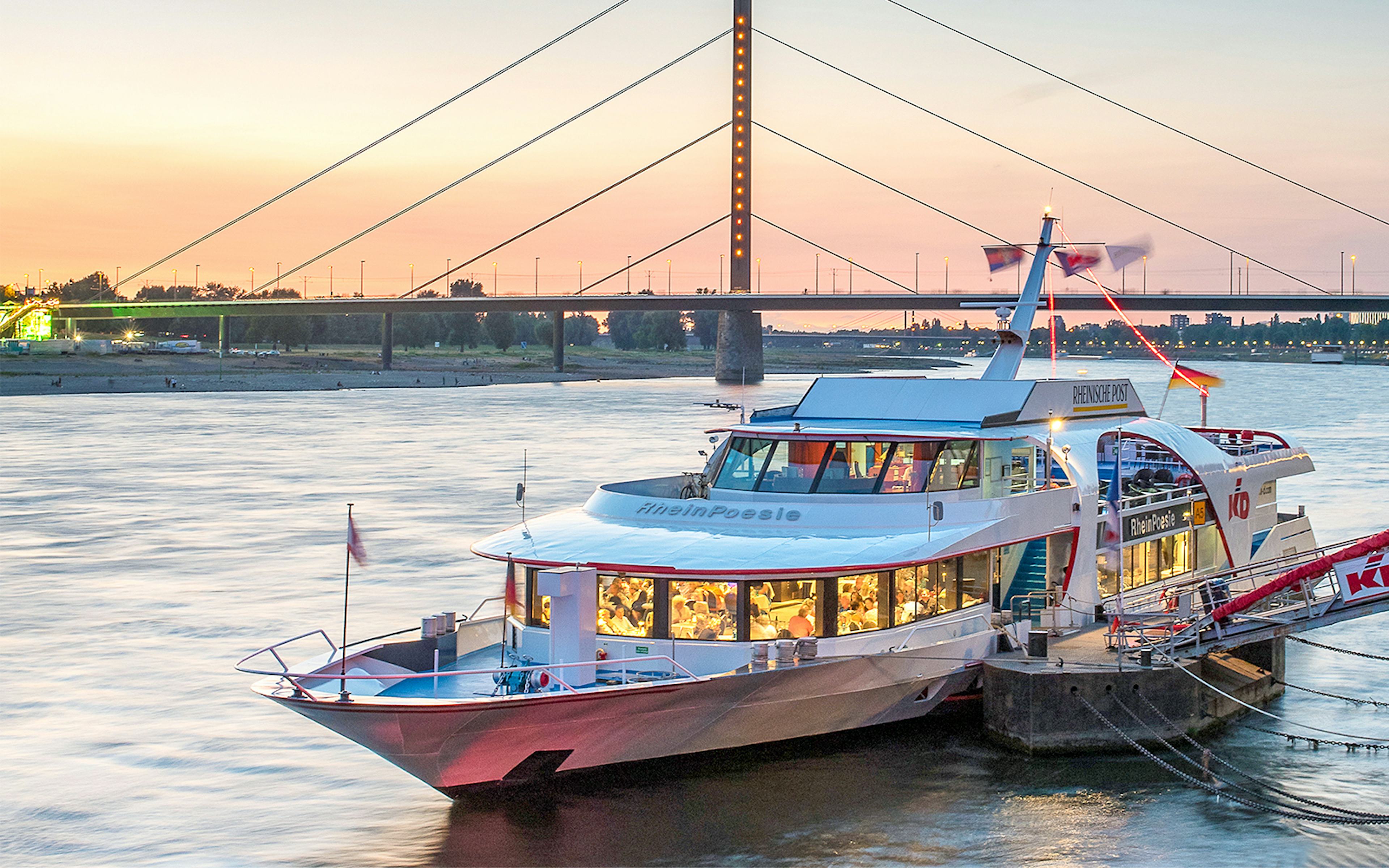 Cruise boat docked on the Rhine River at sunset in Düsseldorf.