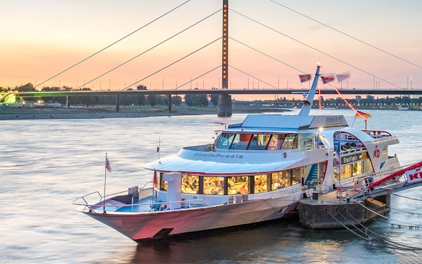 Cruise boat docked on the Rhine River at sunset in Düsseldorf.