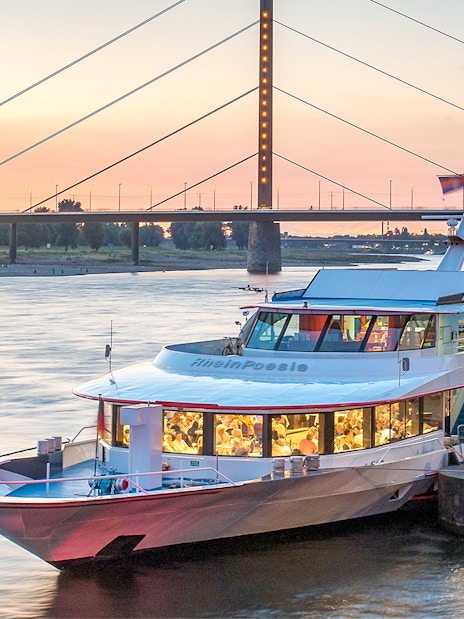 Cruise boat docked on the Rhine River at sunset in Düsseldorf.