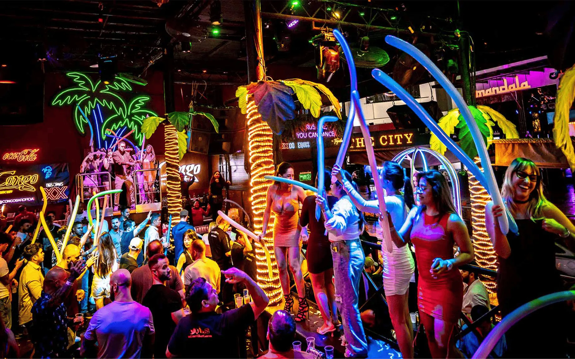 Crowd enjoying vibrant nightlife at Coco Bongo Congo Bar with neon lights and lively atmosphere.