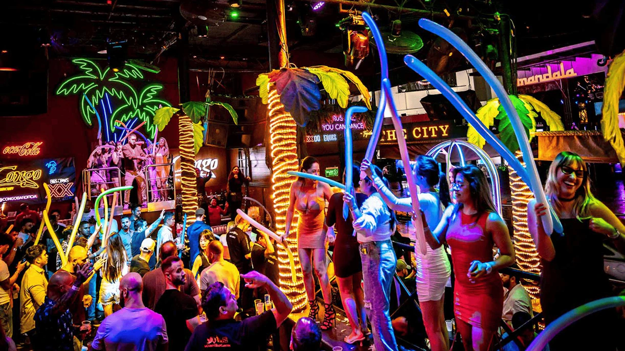 Crowd enjoying vibrant nightlife at Coco Bongo Congo Bar with neon lights and lively atmosphere.