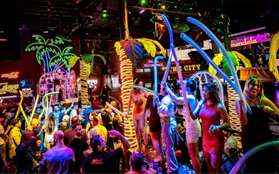Crowd enjoying vibrant nightlife at Coco Bongo Congo Bar with neon lights and lively atmosphere.