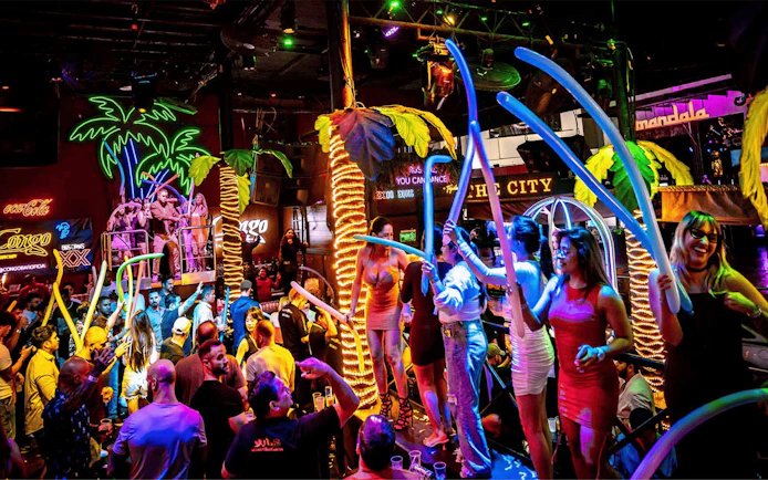 Crowd enjoying vibrant nightlife at Coco Bongo Congo Bar with neon lights and lively atmosphere.