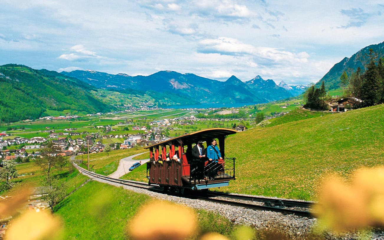 Funicular ascending Mount Stanserhorn with scenic Swiss landscape in the background.