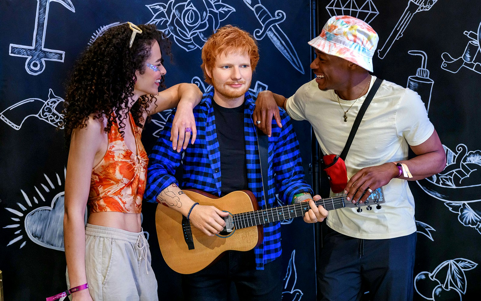 Visitors posing with Ed Sheeran wax figure at Madame Tussauds.