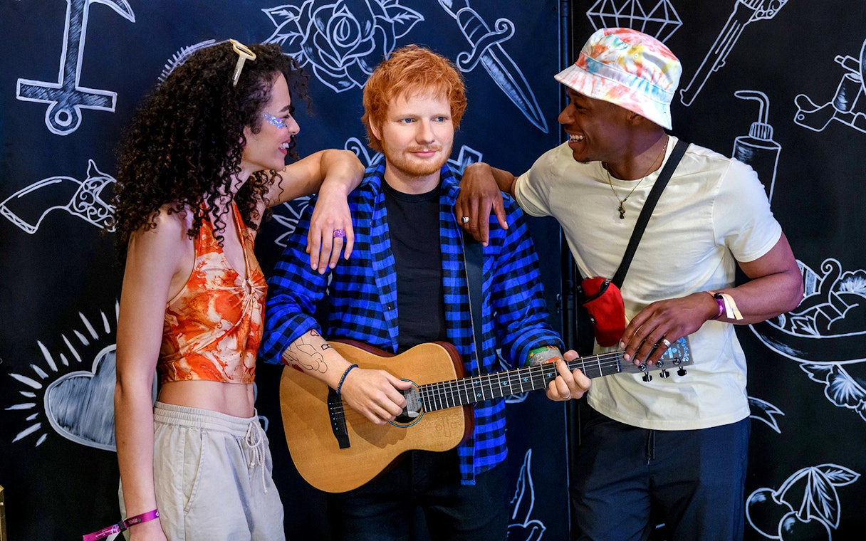 Wax figure of a celebrity with guitar at Madame Tussauds London, surrounded by visitors.