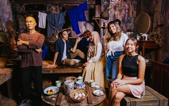 Wax figures and visitors in a historical Singaporean setting at Madame Tussauds Singapore.