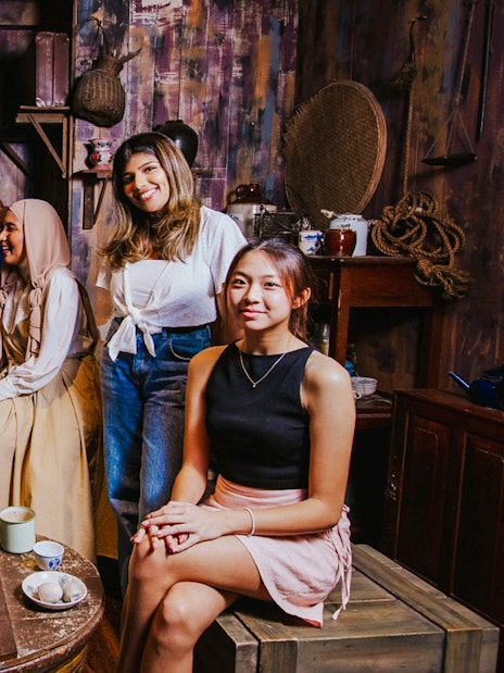 Wax figures and visitors in a historical Singaporean setting at Madame Tussauds Singapore.