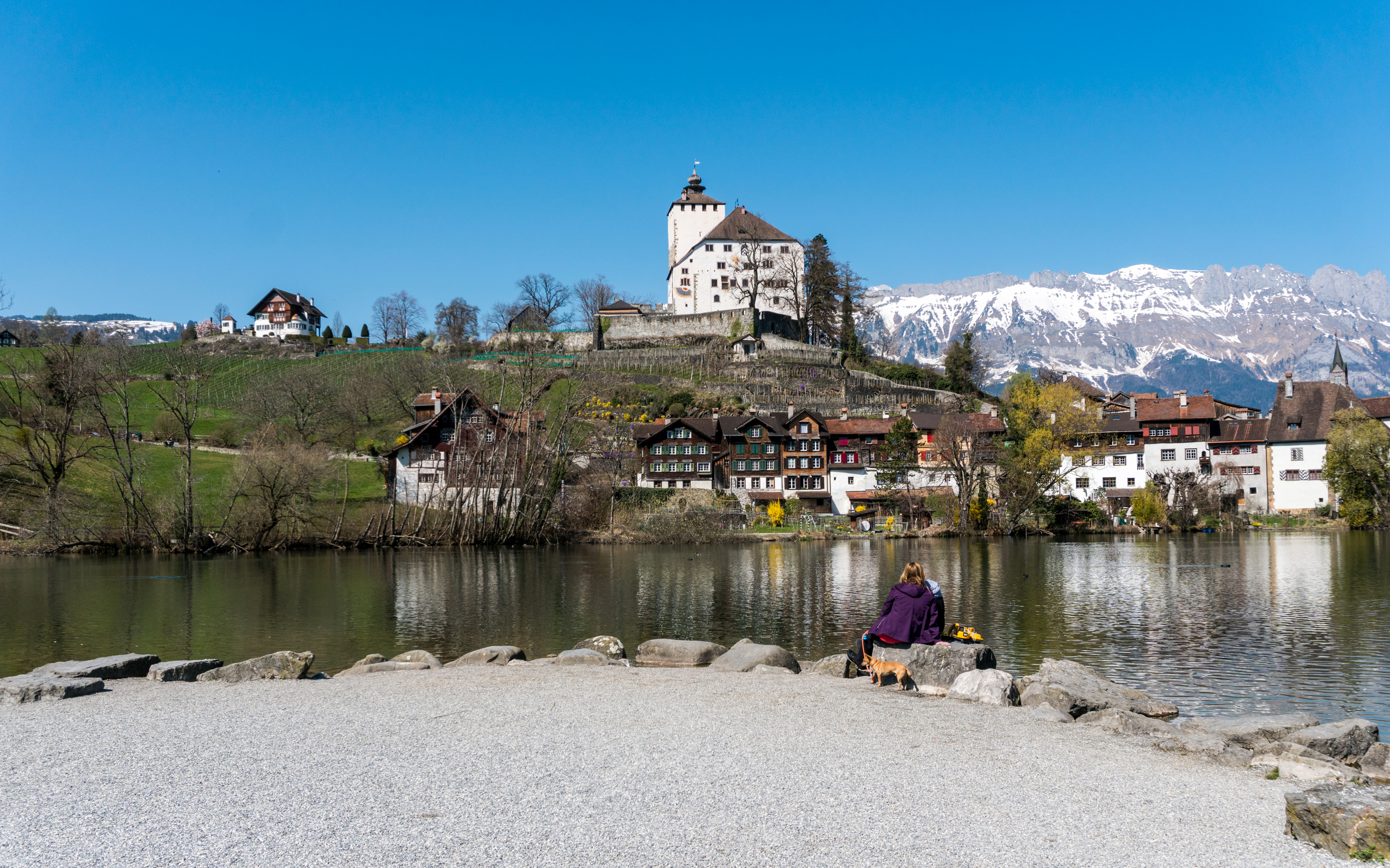 Werdenberg village and lake with historic castle and snow-capped mountains in the background.