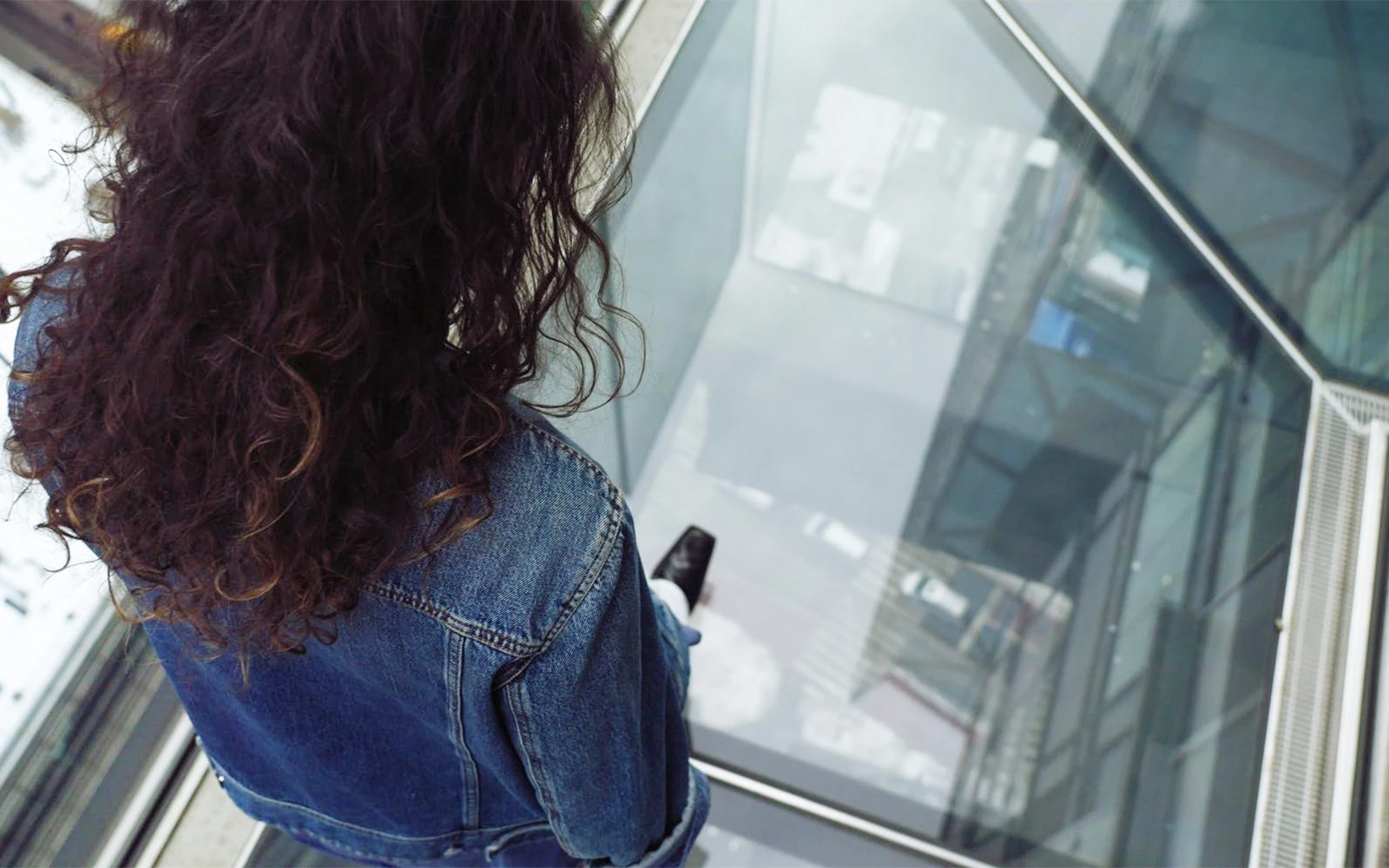 Person standing on One Times Square Skywalk glass floor, looking down at the street below.