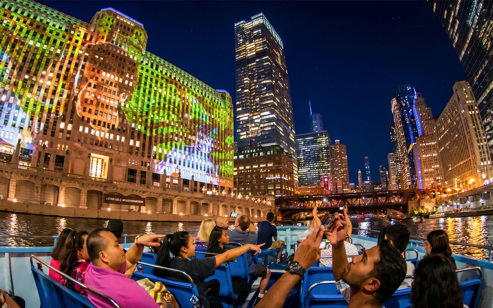 Chicago River cruise at night with city skyline and illuminated buildings.