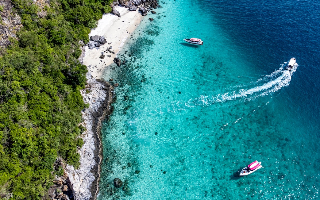 Aerial view of boats near the turquoise waters and rocky shore of Nemo Island, Pattaya.