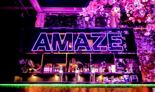 Bar setup with colorful lights and seating in Amaze Amsterdam.