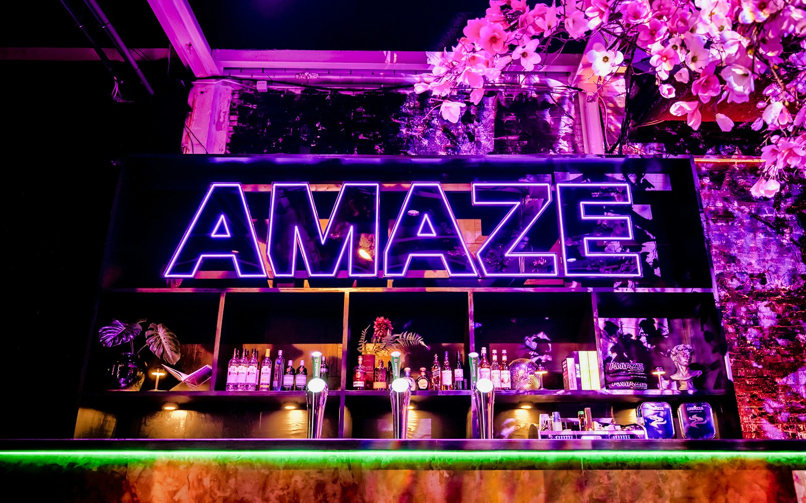 Bar setup with colorful lights and seating in Amaze Amsterdam.