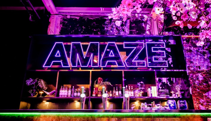 Bar setup with colorful lights and seating in Amaze Amsterdam.