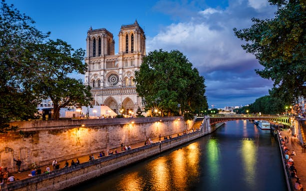 Notre Dame Cathedral and Seine River at dusk in Paris.
