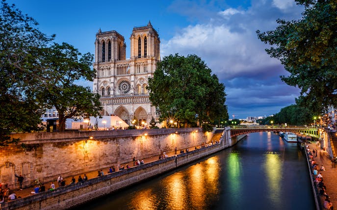 Notre Dame Cathedral and Seine River at dusk in Paris.