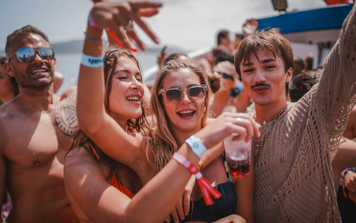 Tourists enjoying a lively Cruise Crush Boat Party with drinks and music.