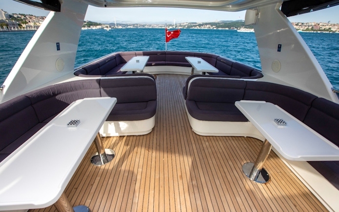 Bosphorus cruise boat deck with seating and tables, Istanbul skyline in background.