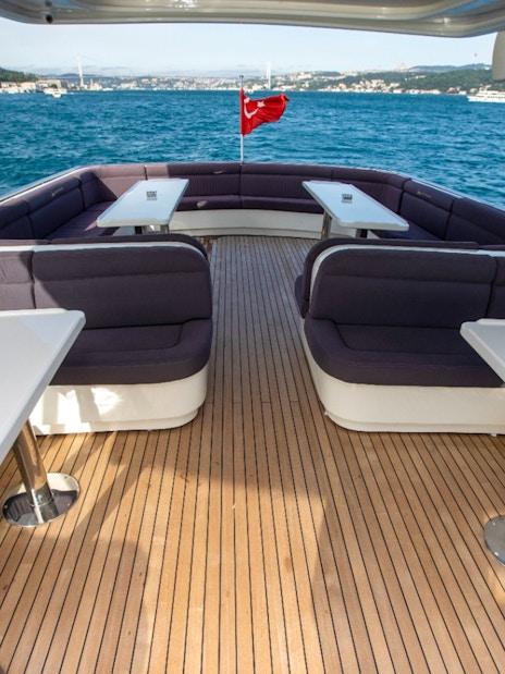 Bosphorus cruise boat deck with seating and tables, Istanbul skyline in background.