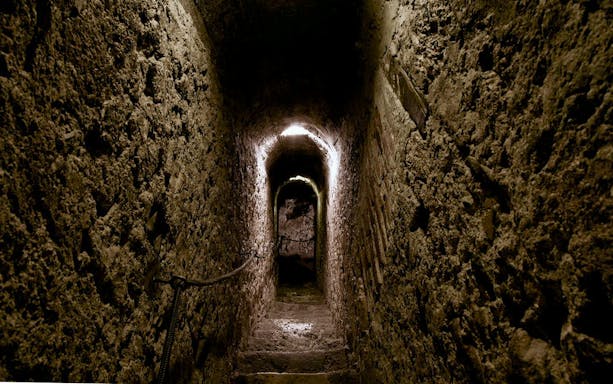 Bran Castle stone passageway with dim lighting and narrow stairs.