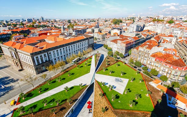 Aerial view of Porto cityscape with red rooftops and green park near Clerigos Tower.