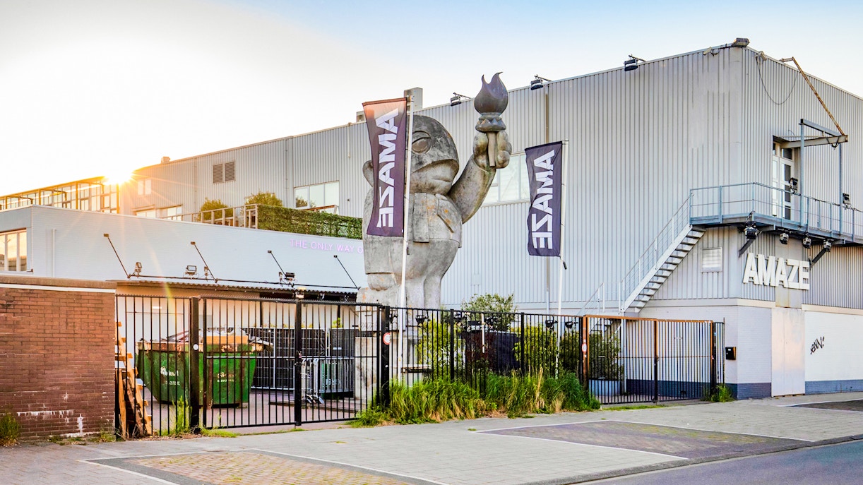 Amaze Amsterdam entrance with large sculpture and flags.