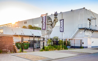 Amaze Amsterdam entrance with large sculpture and flags.