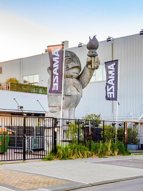 Amaze Amsterdam entrance with large sculpture and flags.