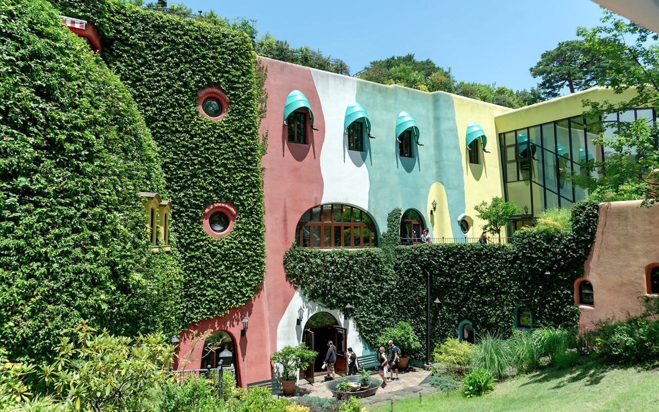 Studio Ghibli Museum exterior with colorful walls and lush greenery in Mitaka, Japan.