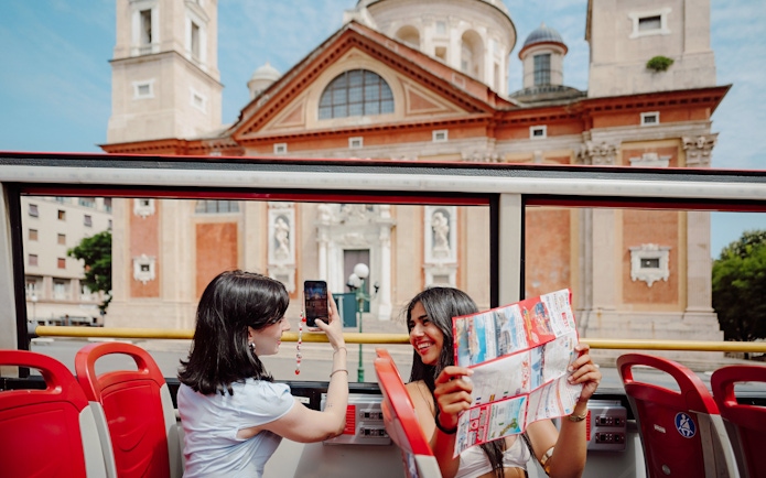 Passengers enjoying a city tour on the City Sightseeing bus in Genova, Italy.