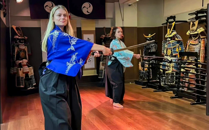 Tourists practicing sword techniques at Samurai Experience in Japan.