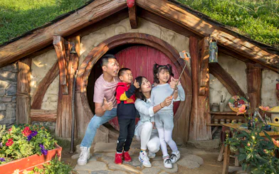 Family taking a selfie at Hobbiton Movie Set entrance, Auckland tour.