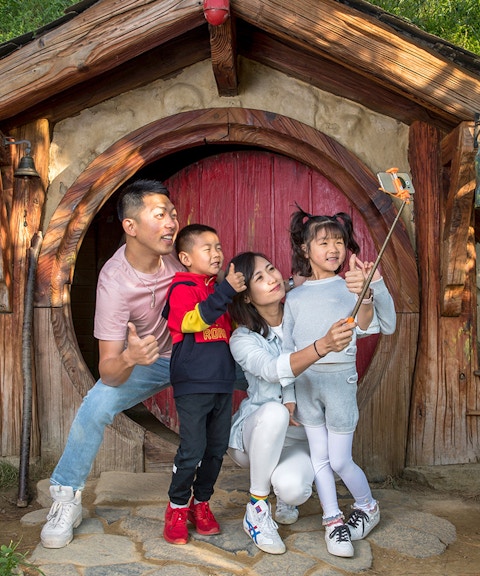 Family taking a selfie at Hobbiton Movie Set entrance, Auckland tour.