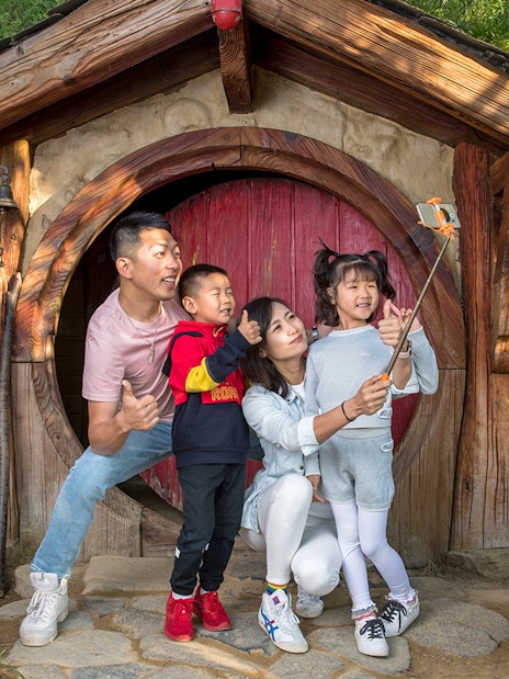 Family taking a selfie at Hobbiton Movie Set entrance, Auckland tour.
