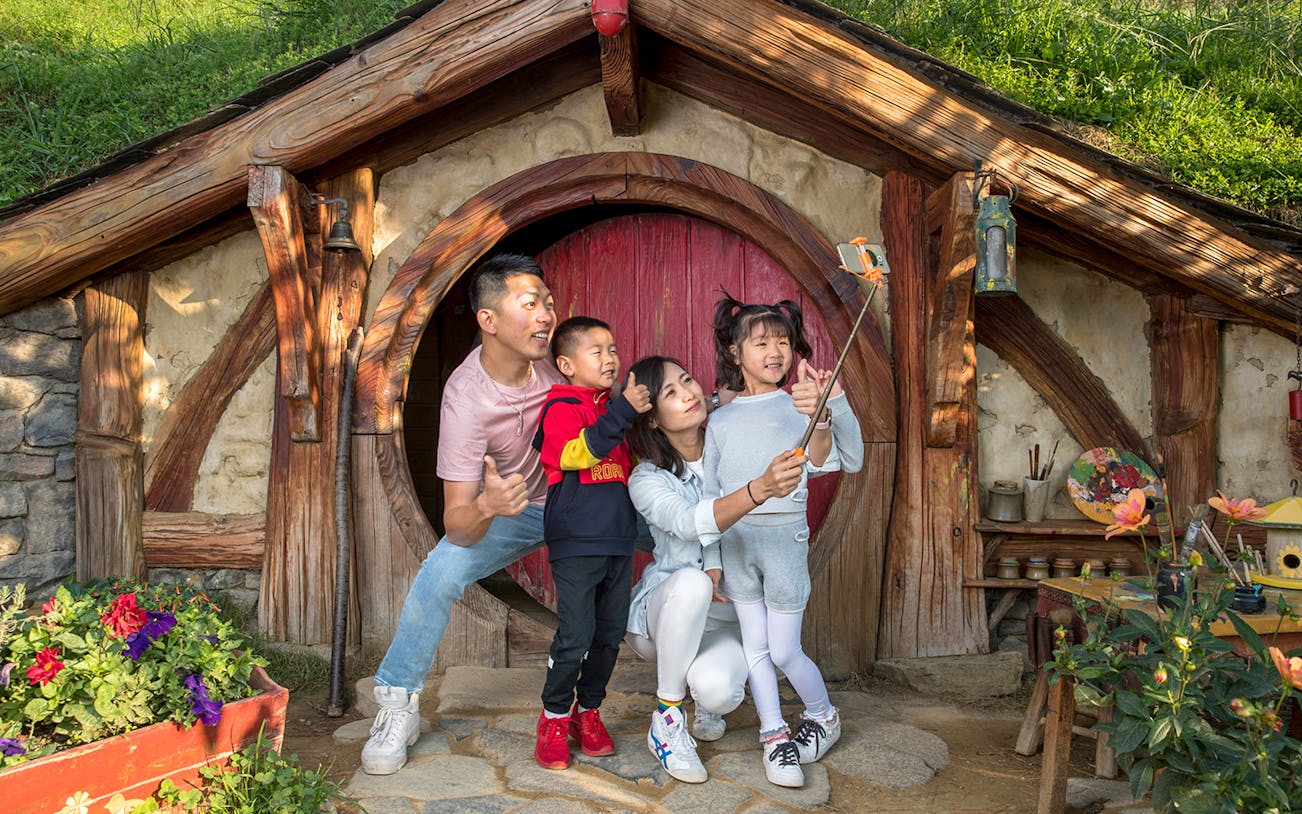 Family taking a selfie at Hobbiton Movie Set entrance, Auckland tour.