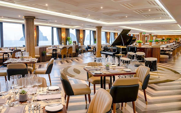 Elegant dining area with a grand piano on the Ambassador cruise restaurant.