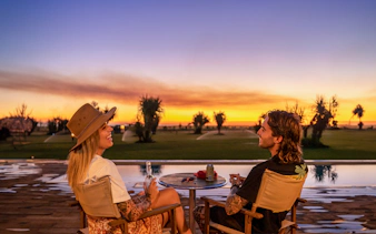 Couple enjoying sunset by pool at Top End Safari Camp, Finniss River.